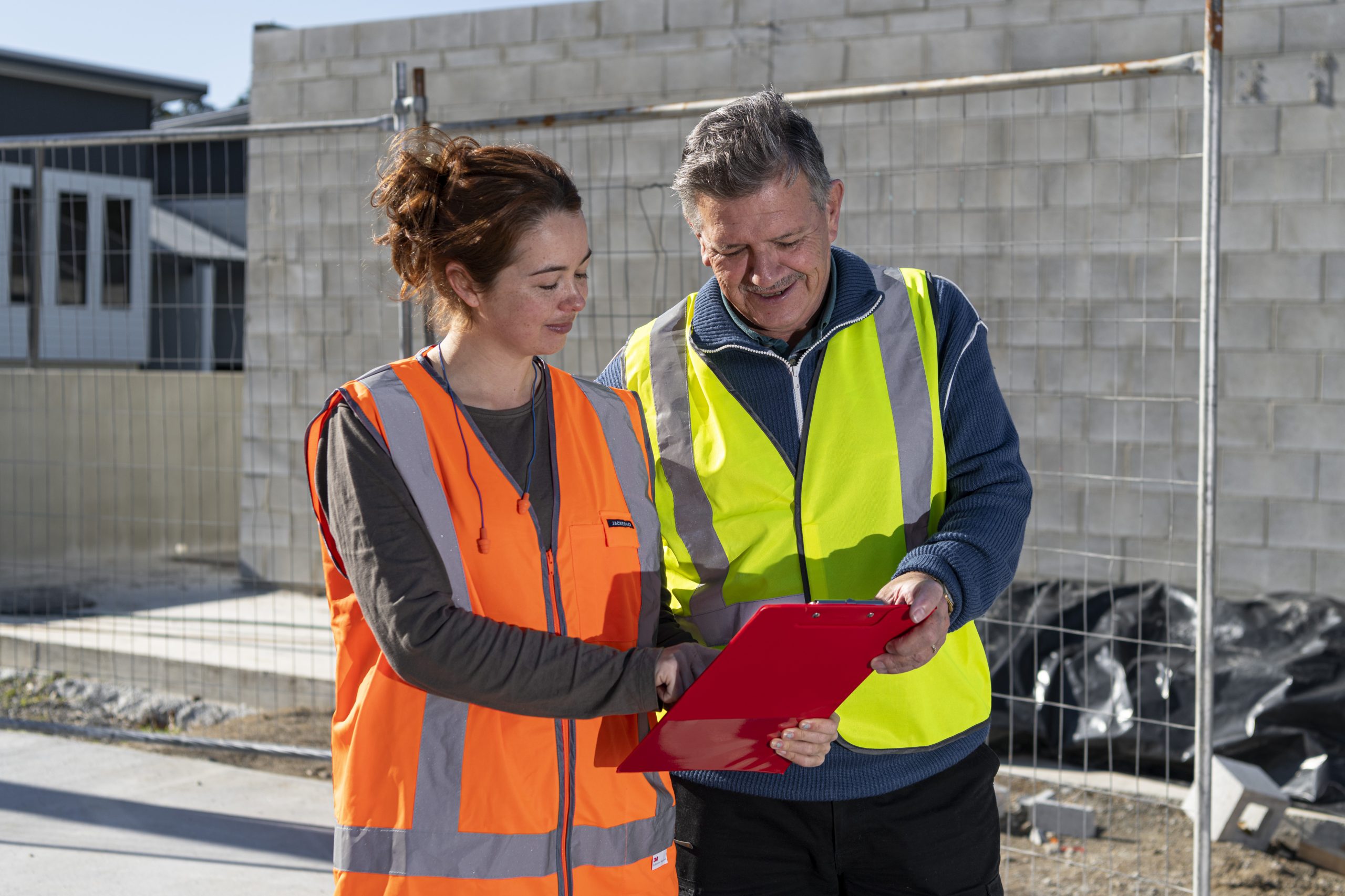 Man and woman in high vis looking at a clipboard